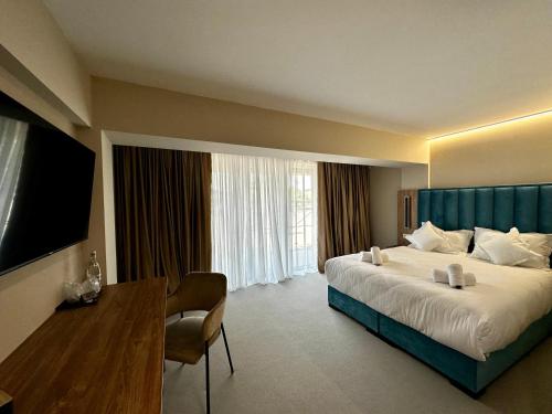 DrăgăşaniRiver Park Hotel的酒店客房设有一张大床和一张书桌。