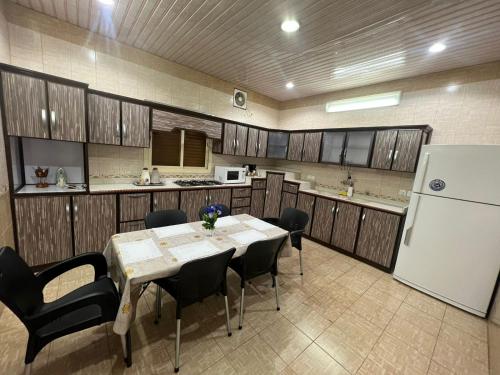 塔伊夫شقةكبيره 4 غرف منها 3 غرف نوم اطلاه مجلس صالة 4-room apartment, including 3 bedrooms, a living room, a sitting room, and a view的厨房配有桌椅和冰箱。