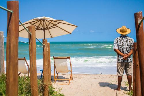 拉巴拉德纳圣米格尔薇瓦巴拉酒店的一位站在海滩上的人,拿着一把遮阳伞和椅子