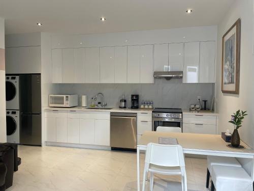 温哥华Brand new 1Queenbed family suite near UBC的厨房配有白色橱柜和桌椅