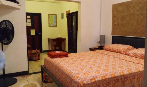 圣伊格纳西奥Maxroomz的一间卧室配有一张带橙色毯子的床