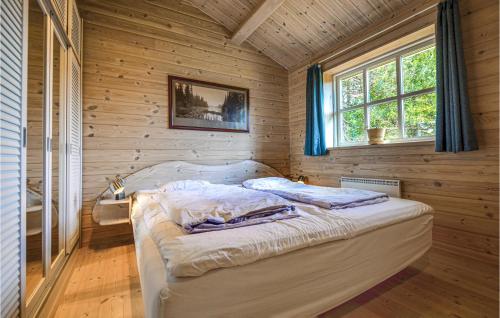 埃贝尔托夫特Nice Home In Ebeltoft With Kitchen的卧室配有一张床铺,位于带木墙的房间内