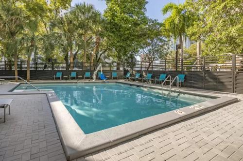 迈阿密Comfort Inn & Suites Downtown Brickell-Port of Miami的一个带蓝色椅子和树木的游泳池
