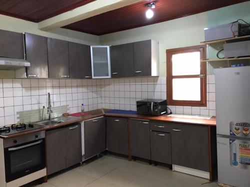 班基Villa Sophie à Sassara Pk 12 Bangui的厨房配有灰色橱柜、水槽和冰箱。