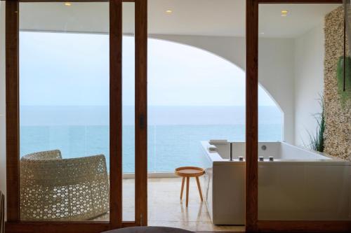 卡农Elite Atoll Khanom - Luxury Coastal Escape的一间带浴缸和椅子的浴室,享有海景。