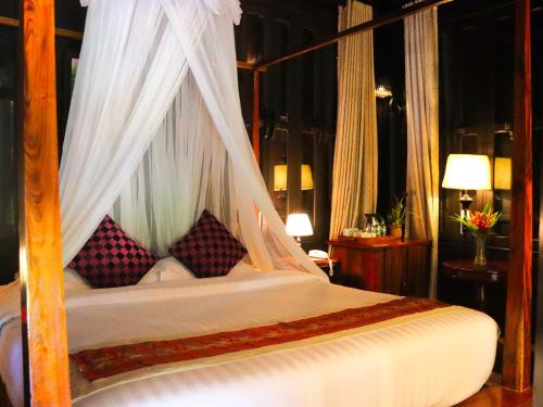 琅勃拉邦Namkhan View Luangprabang Resort的卧室配有带枕头的天蓬床