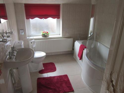 Longtown梧桐树乡村别墅的浴室配有盥洗盆、卫生间和浴缸。