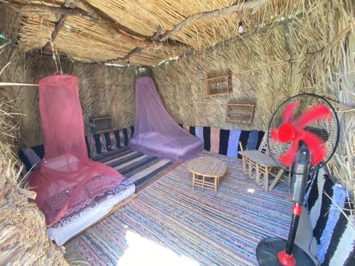 锡瓦Maya Corner的一间位于稻草小屋内的房间,配有两张床和椅子