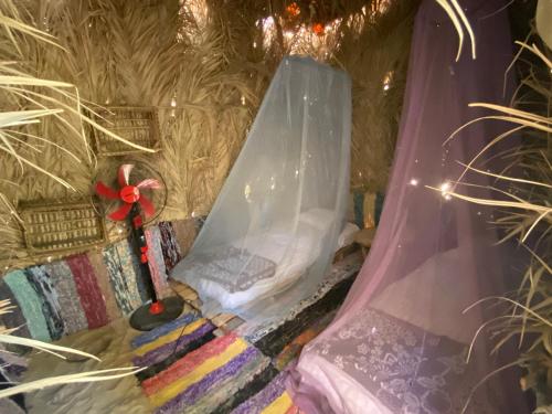 锡瓦Maya Corner的一间设有一张带面纱和花瓶的床的房间