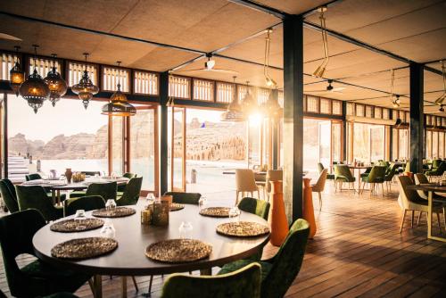 欧拉Our Habitas AlUla的用餐室配有桌椅和大窗户