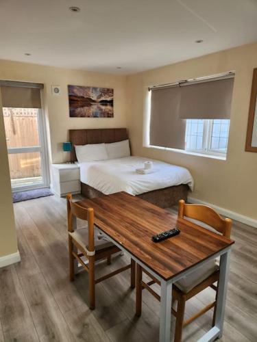 贝克斯利黑思Beautiful private en-suite room with its own entry的一间卧室配有一张床和一张木桌及椅子