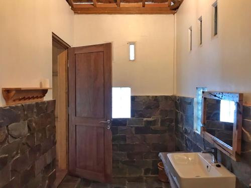 武吉拉旺Rambai Tree Jungle Lodges的一间带木门和水槽的浴室