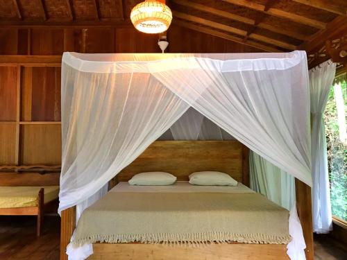 武吉拉旺Rambai Tree Jungle Lodges的一张带白色窗帘的天蓬床