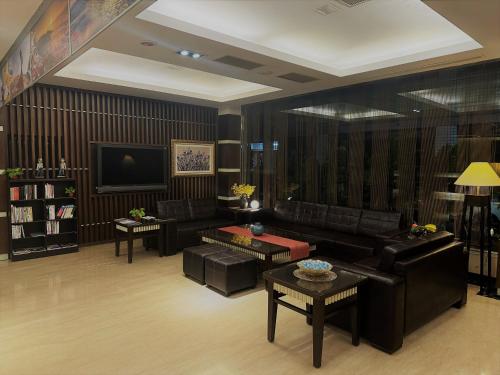 台南扬悦精致大饭店台南馆的客厅配有黑色皮革家具和电视