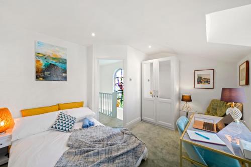 伦敦3 Bedroom Mews Home - Clapham Common - Free Private Parking - Sleeps 5 - Newly Refurbished - Sweetpea & Pillow Properties的一间卧室配有一张床和一张带笔记本电脑的书桌