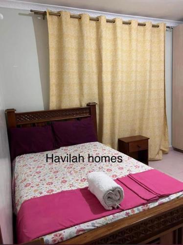 Kitengela Havilla homes的一间卧室,床上有鹰派房屋的标志