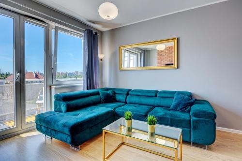 什切青Allure Nautica Aparthotel的客厅配有蓝色的沙发和桌子