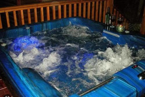 梅图拉בקתות עץ סקנדינביות במטולה的蓝色的浴缸,里面装满了水和一瓶葡萄酒