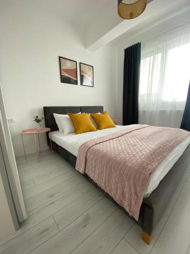 布加勒斯特Orhideea Central Apartments的一间卧室配有一张带黄色枕头的床和一扇窗户