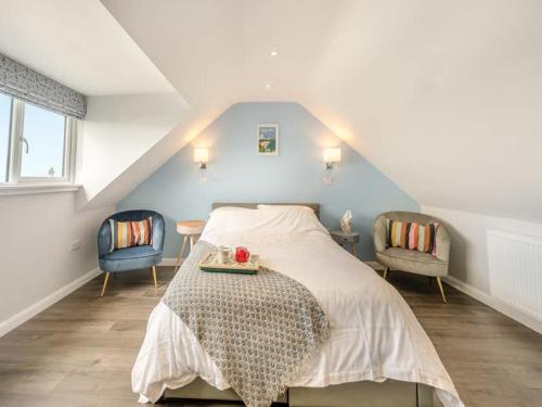 彭布罗克郡Sea View Luxury 5 Star Cottage Near Milford Marina的一间卧室配有一张床和两把椅子