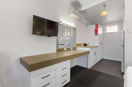 阿德莱德Econo Lodge East Adelaide的厨房配有白色橱柜和平面电视。