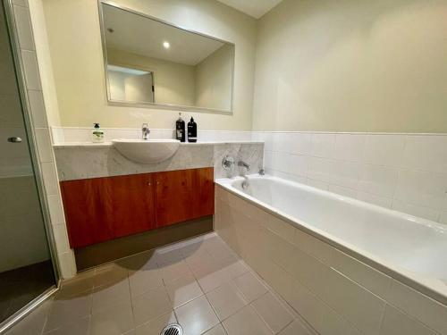 悉尼North Sydney 2 Bedroom - Pool Parking Gym Spa Sleeps 6的一间带水槽、浴缸和镜子的浴室