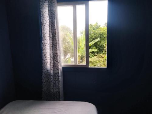 罗索Ian Creole Garaden Cottages的窗户,带床和窗帘的房间