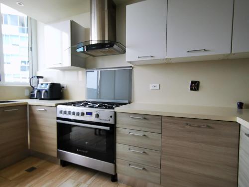 巴拿马城Beautiful Apartment 2 BR的厨房配有炉灶和木制橱柜。