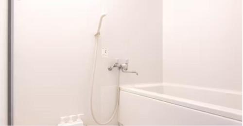 东京メゾン・ド・ミナ的白色浴室内带软管的淋浴