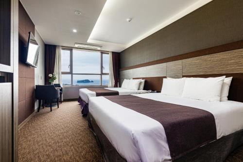 西归浦市Eastern Hotel Jeju的酒店客房设有两张床和窗户。