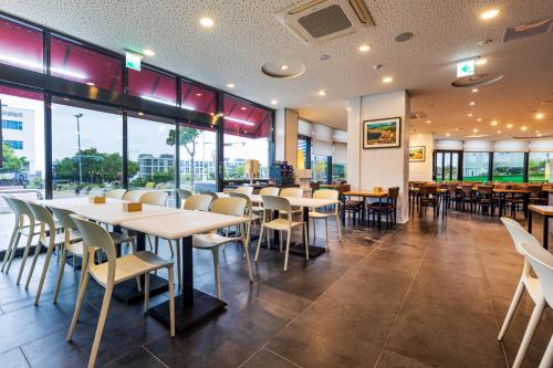 西归浦市Eastern Hotel Jeju的餐厅设有桌椅和窗户。