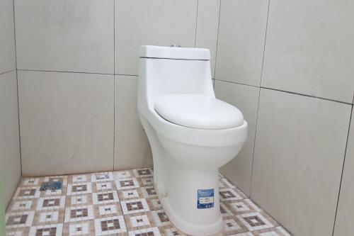 KebumenOYO 93025 Surya Abadi Homestay Syariah的浴室设有白色卫生间,位于瓷砖墙壁上