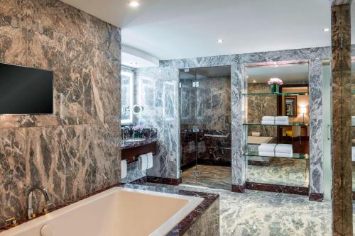 马斯喀特阿曼喜来登酒店的带浴缸的浴室和墙上的电视