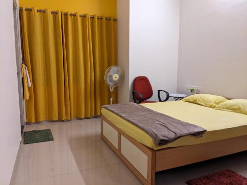 迈索尔Athreyas@60/A的一间卧室配有一张带黄色窗帘的床和风扇
