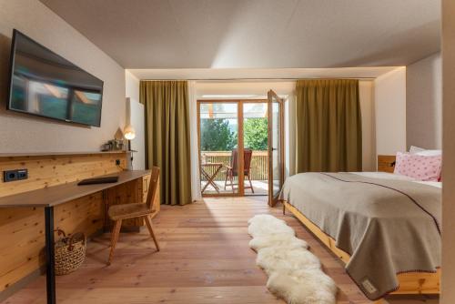 Sankt WolfgangSeetalblick的一间带一张床和一张书桌的卧室以及一个阳台