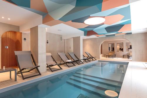 夏蒙尼-勃朗峰Chalet Hôtel Le Prieuré & Spa的一个带椅子的游泳池以及带壁画的天花板