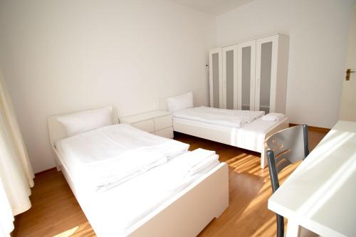 贝尔吉施格拉德巴赫Apartment Centrum Bergisch Gladbach的配有白色墙壁和木地板的客房内的两张床