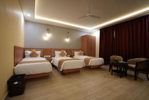 巴特那The Royal Bihar的酒店客房带两张床和一张桌子以及椅子。