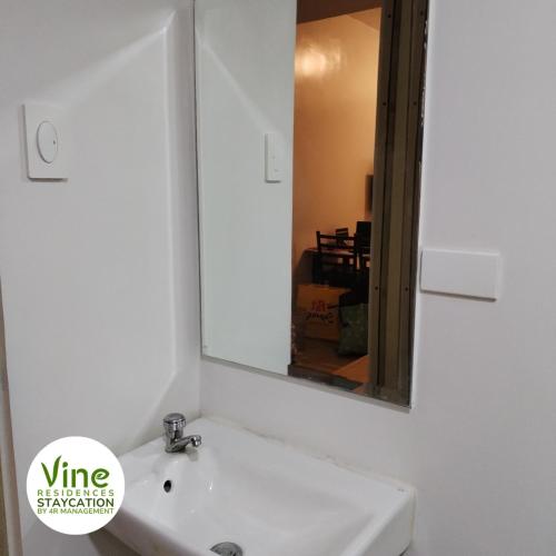 马尼拉Vine Residences Staycation的浴室设有白色水槽和镜子