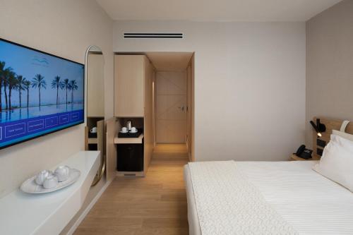 提比里亚盖海滩酒店的卧室配有白色的床和墙上的电视