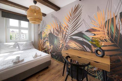 托伦AtHome Toruń Apartamenty的一间卧室配有一张床、一张书桌和一个壁画