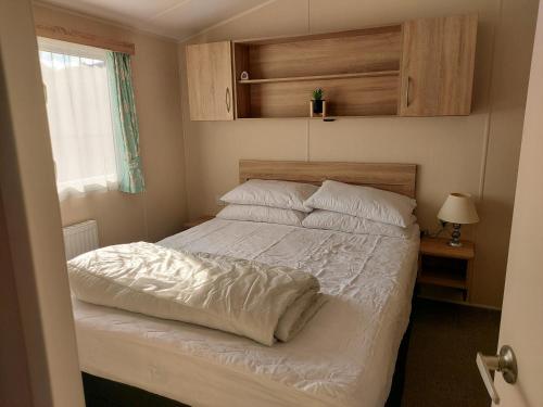布里恩2 Brightholme 6 berth with Decking & enclosed gard的一间卧室配有带白色床单和枕头的床。
