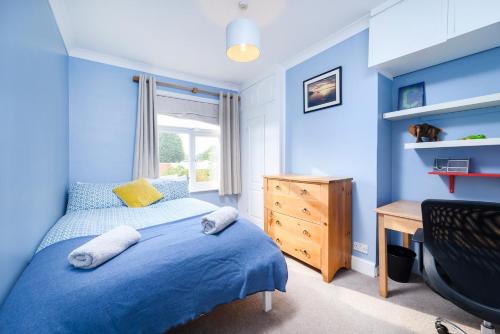 伦敦Modern 3 bedroom house with garden view的一间卧室设有蓝色的墙壁、一张床和一张书桌