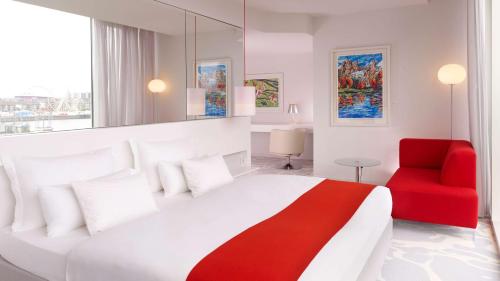 科隆art'otel cologne, Powered by Radisson Hotels的一间卧室配有一张大床和一张红色椅子