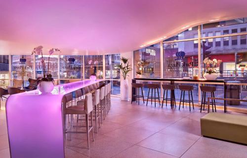 诺丁汉公园广场诺丁汉酒店的餐厅设有酒吧,配有椅子和紫色照明