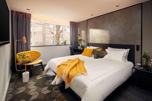 阿姆斯特丹公园广场酒店&度假村的卧室配有一张白色大床和一把椅子