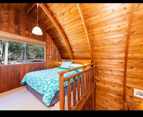 楠立Jarrah Glen Cabins的小木屋内一间卧室,配有一张床