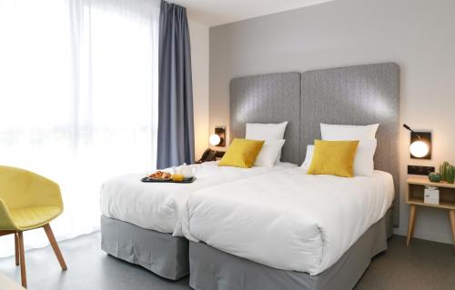 昂热Odalys City Angers Centre Gare的卧室配有一张带黄色枕头的大型白色床。