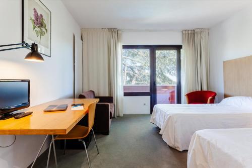 科尔百托Checkin Montserrat的酒店客房设有两张床和一张带电脑的书桌