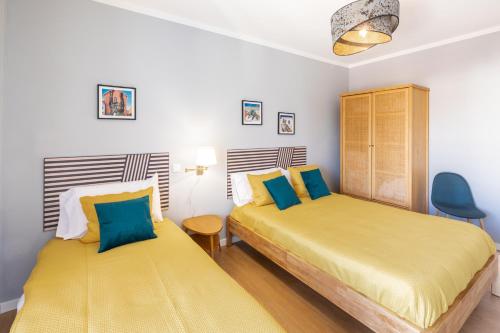 法蒂玛Modern 3 bedrooms 3 bath apartment 5 minutes walk from the Santuary的一间卧室配有两张带黄色和蓝色枕头的床